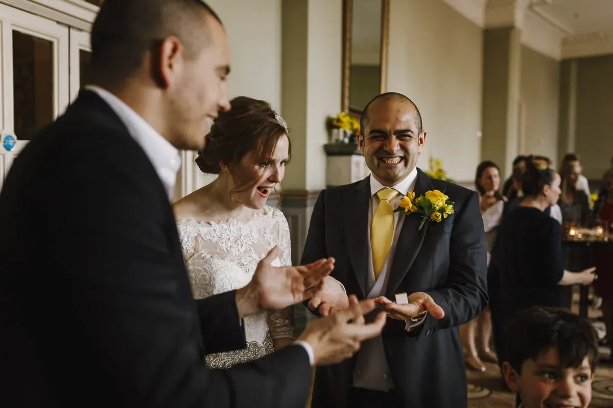 A bride and groom laughing in amazement as magician Matt Parro reveals a trick