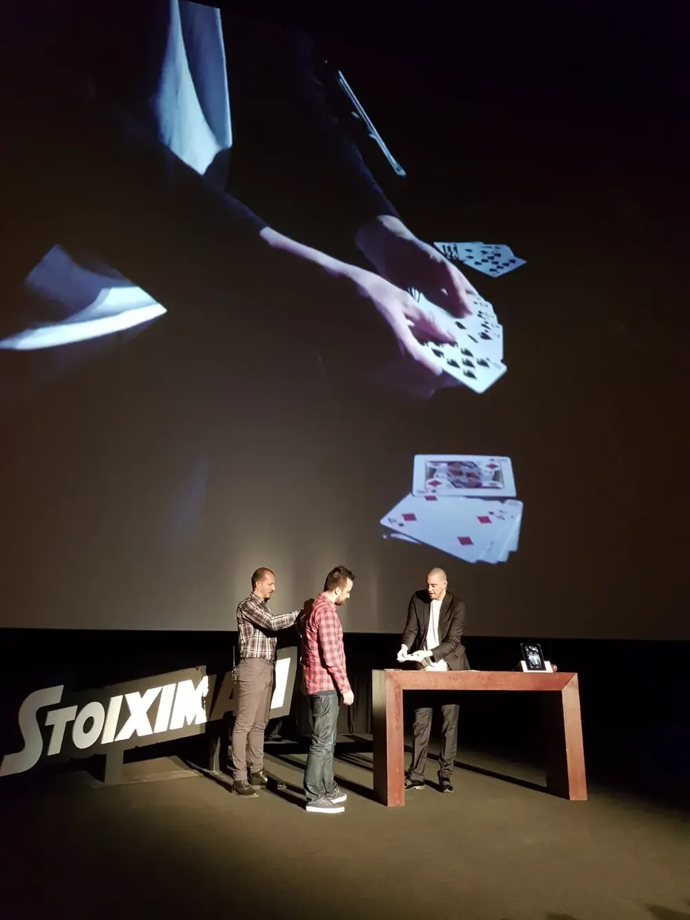 A card trick shown on the big screen at a conference