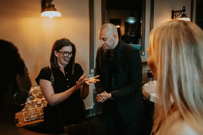 A guest clapping in delight at Matt Parrou2019s card trick at a private party