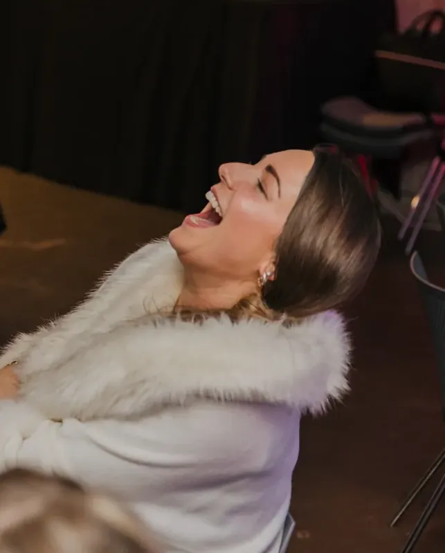 A guest laughing at a black-tie dinner