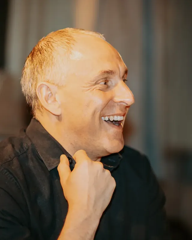 A party guest laughing with his hand on his chest