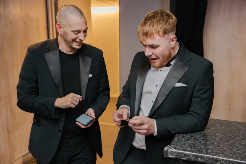 Black-tie guest checking his phone during Matt Parrou2019s mind-reading trick
