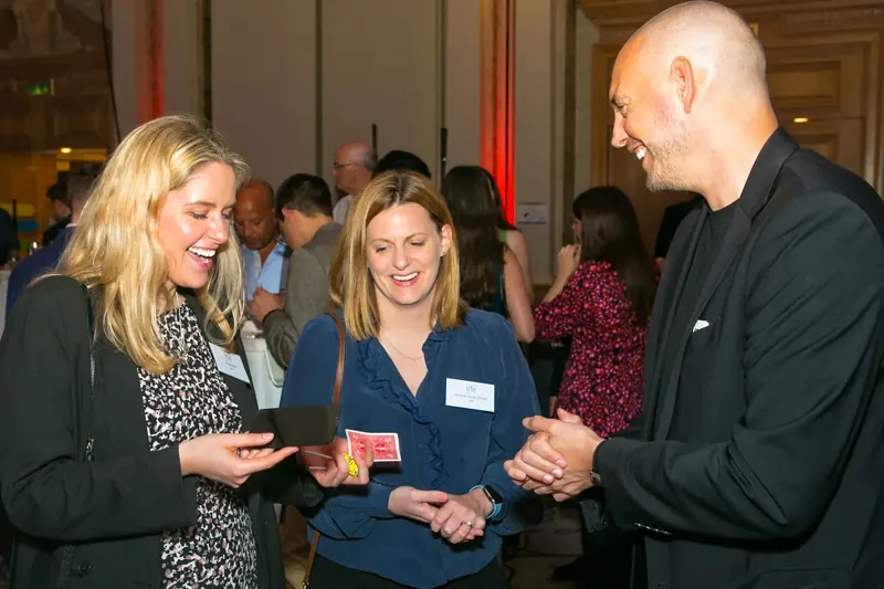 Delegates laughing at a card trick at a corporate event