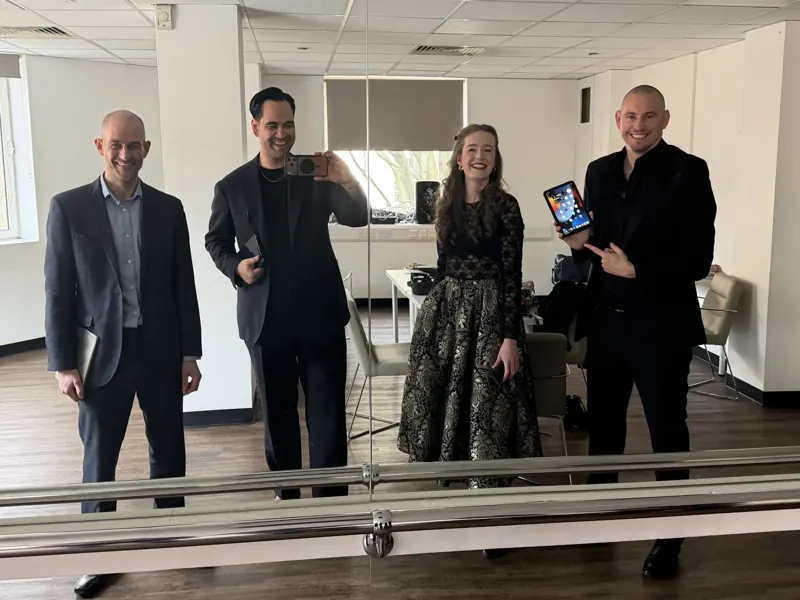 Four performers rehearsing together in a studio mirror