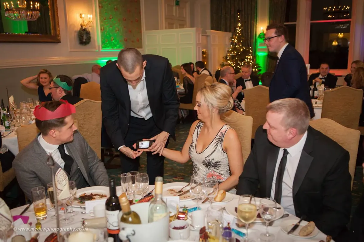Guests at a Christmas dinner table watching close-up magic