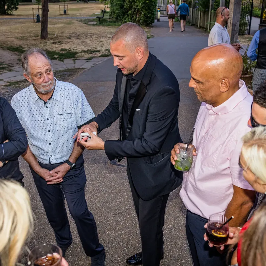 Guests gathered round Matt Parro for a trick at an outdoor party