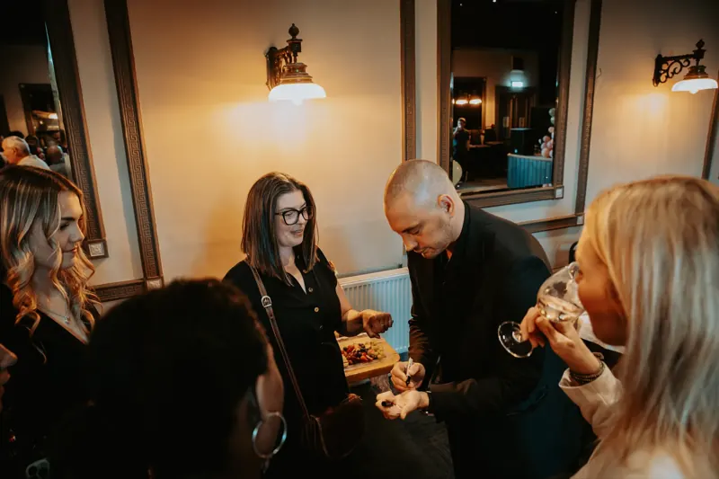 Guests watching Matt Parrou2019s card trick at a party