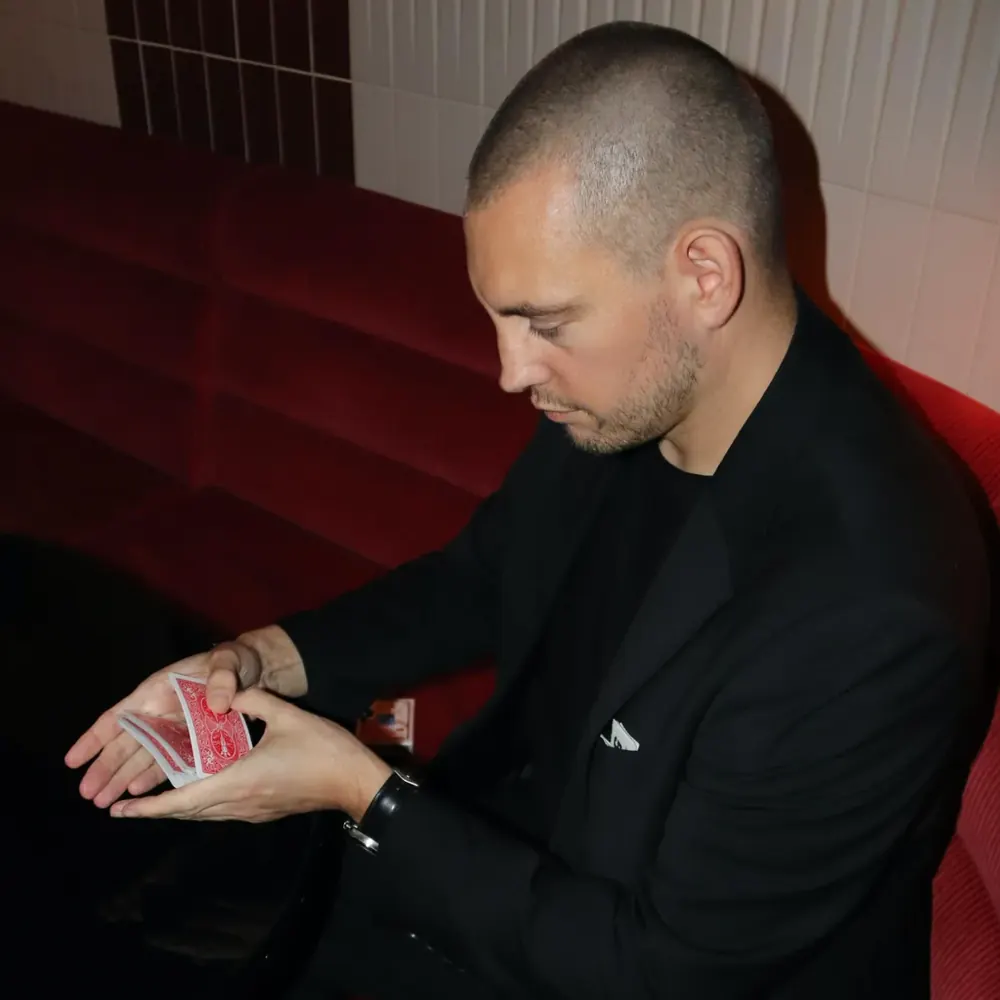 Magician Matt Parro holding playing cards in a red velvet booth
