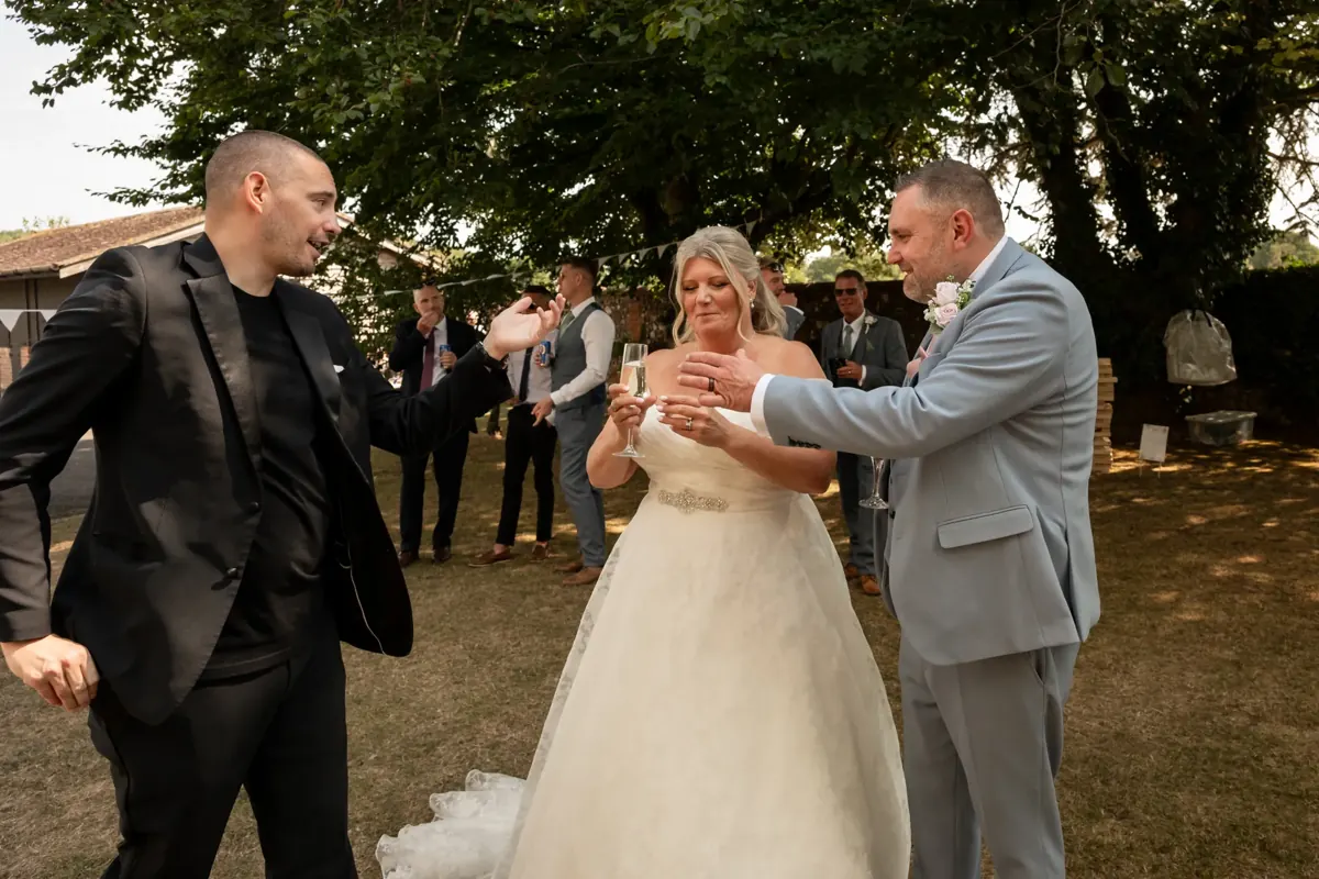 Matt Parro performing a trick for a bride and groom in a garden at their wedding, with guests watching
