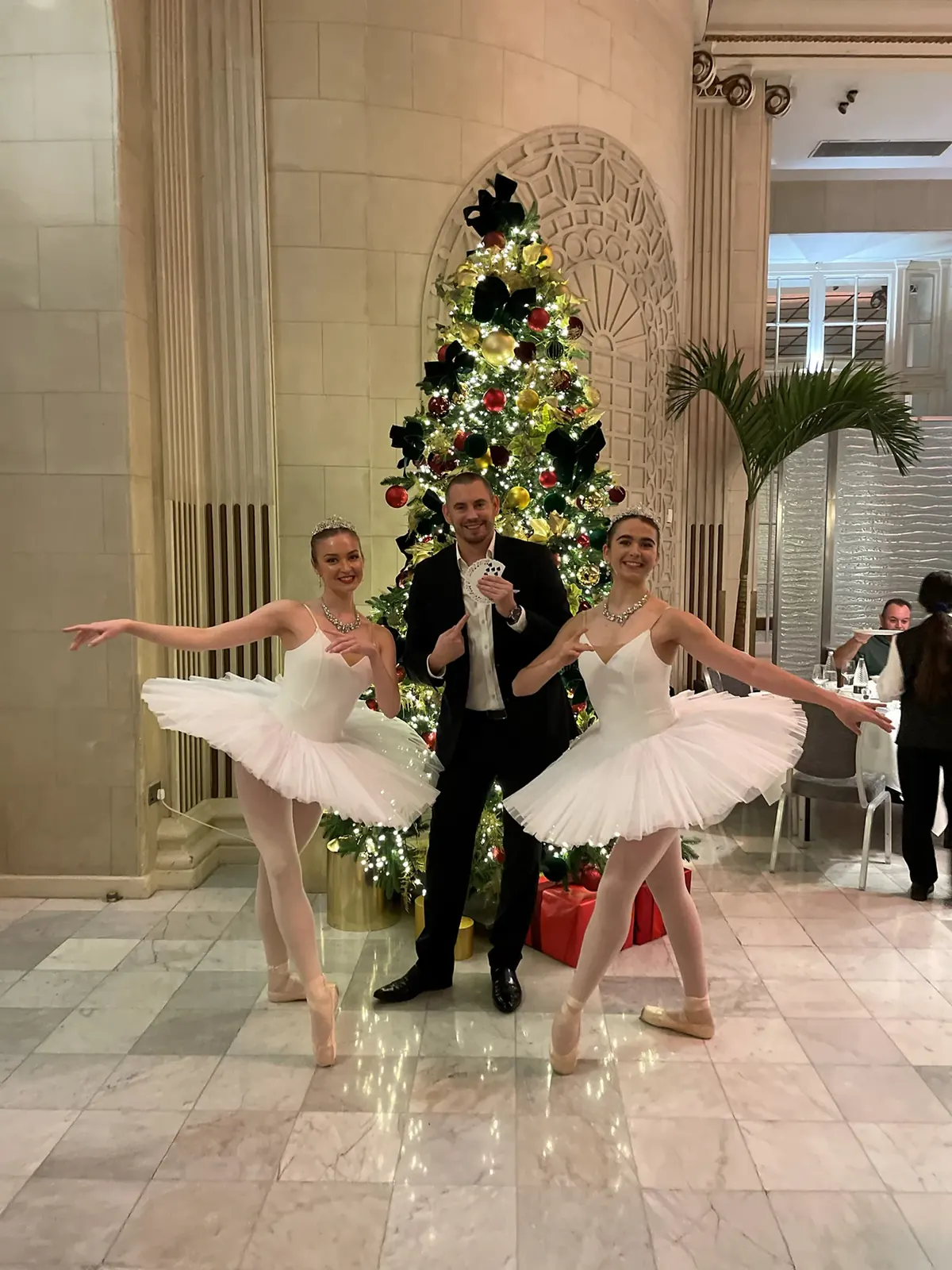 Matt Parro performing at a Christmas party in a hotel with ballet dancers by the Christmas tree