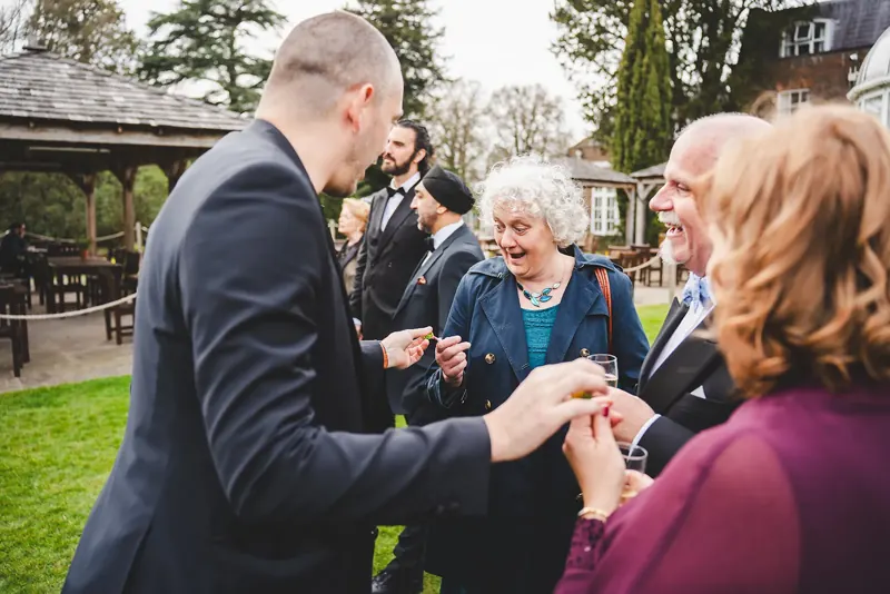 Older wedding guests amazed by Matt Parrou2019s magic in a garden