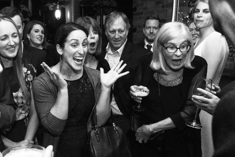 Party guests screaming at a close-up magic trick, black and white
