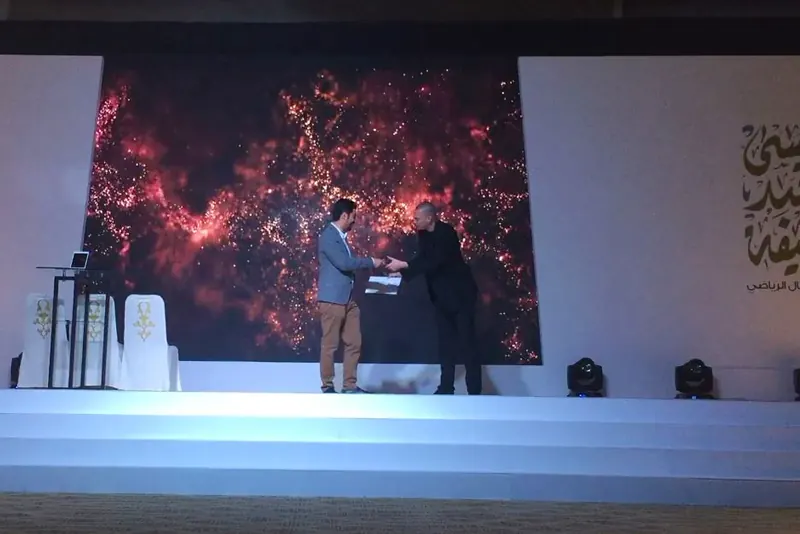 Stage magician Matt Parro with a volunteer under dramatic gala lighting