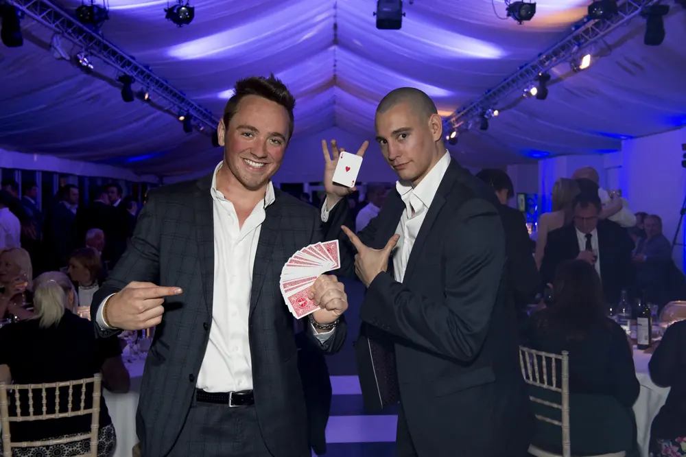 Two magicians with fans of cards at a marquee gala
