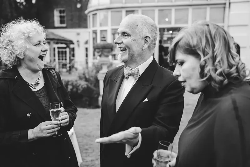 Wedding guests laughing in the garden, black and white